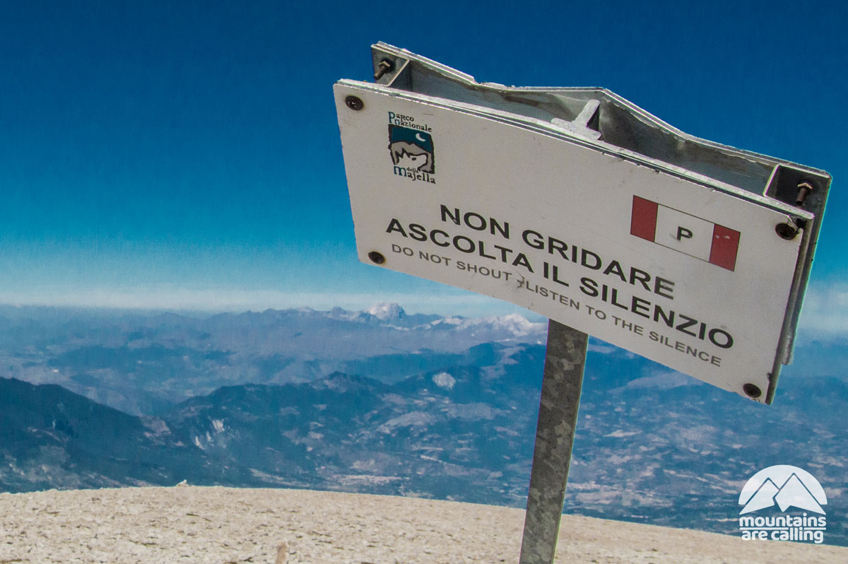 Cartello ascolta il silenzio con dietro un panorama sul Gran Sasso, visto dal Monte Amaro